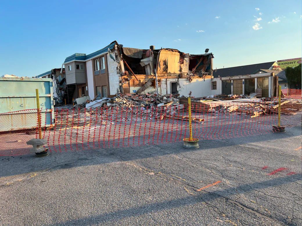 A large house is being demolished in a parking lot.