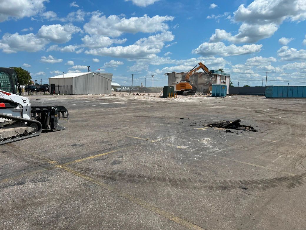 A bulldozer is parked in a parking lot with a building in the background.