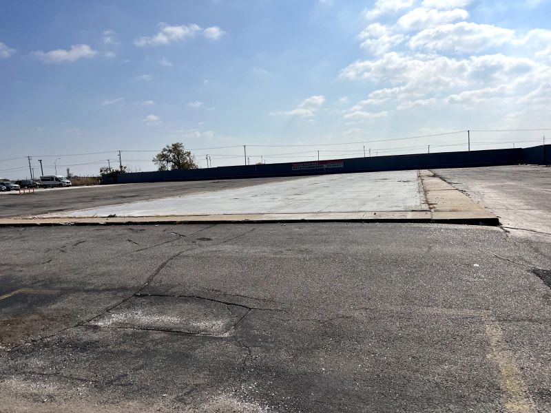 An empty parking lot with a blue fence in the background