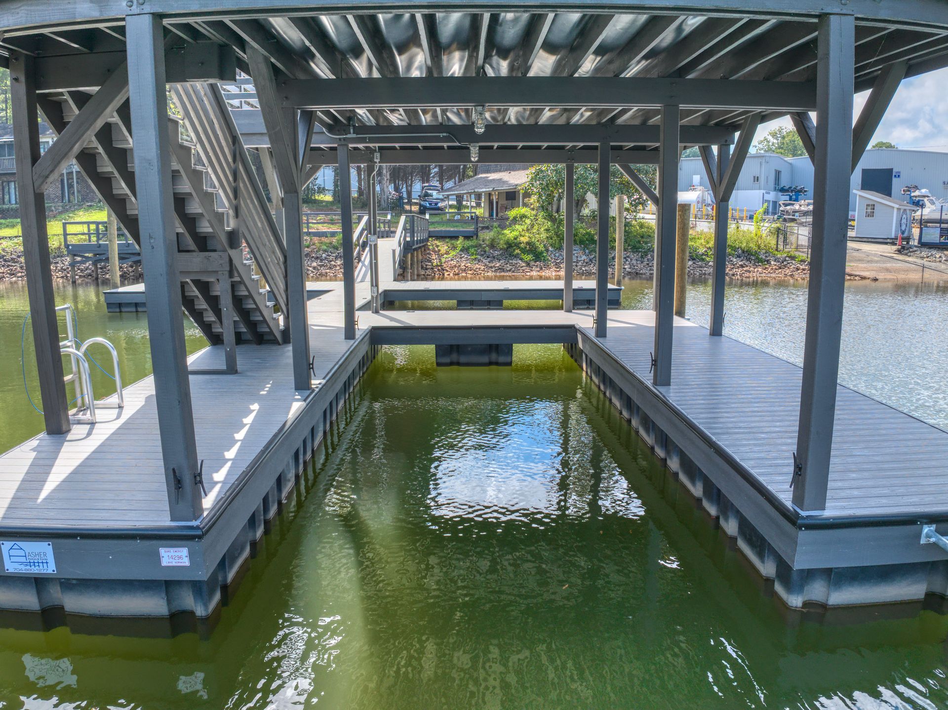 Dock with covered slip on a lake; gray and brown with stairs leading up.
