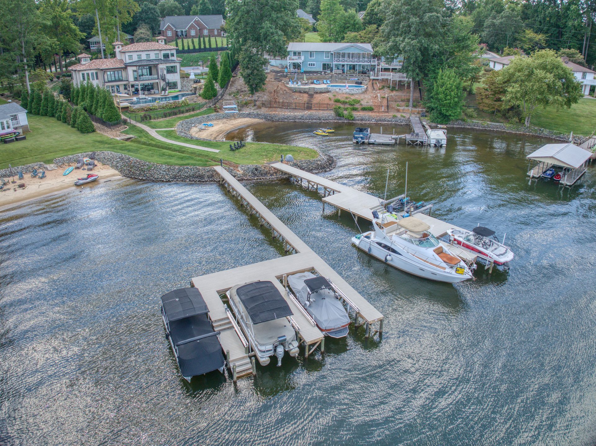 Aerial view of a lake with docks, boats, and shoreline with houses.