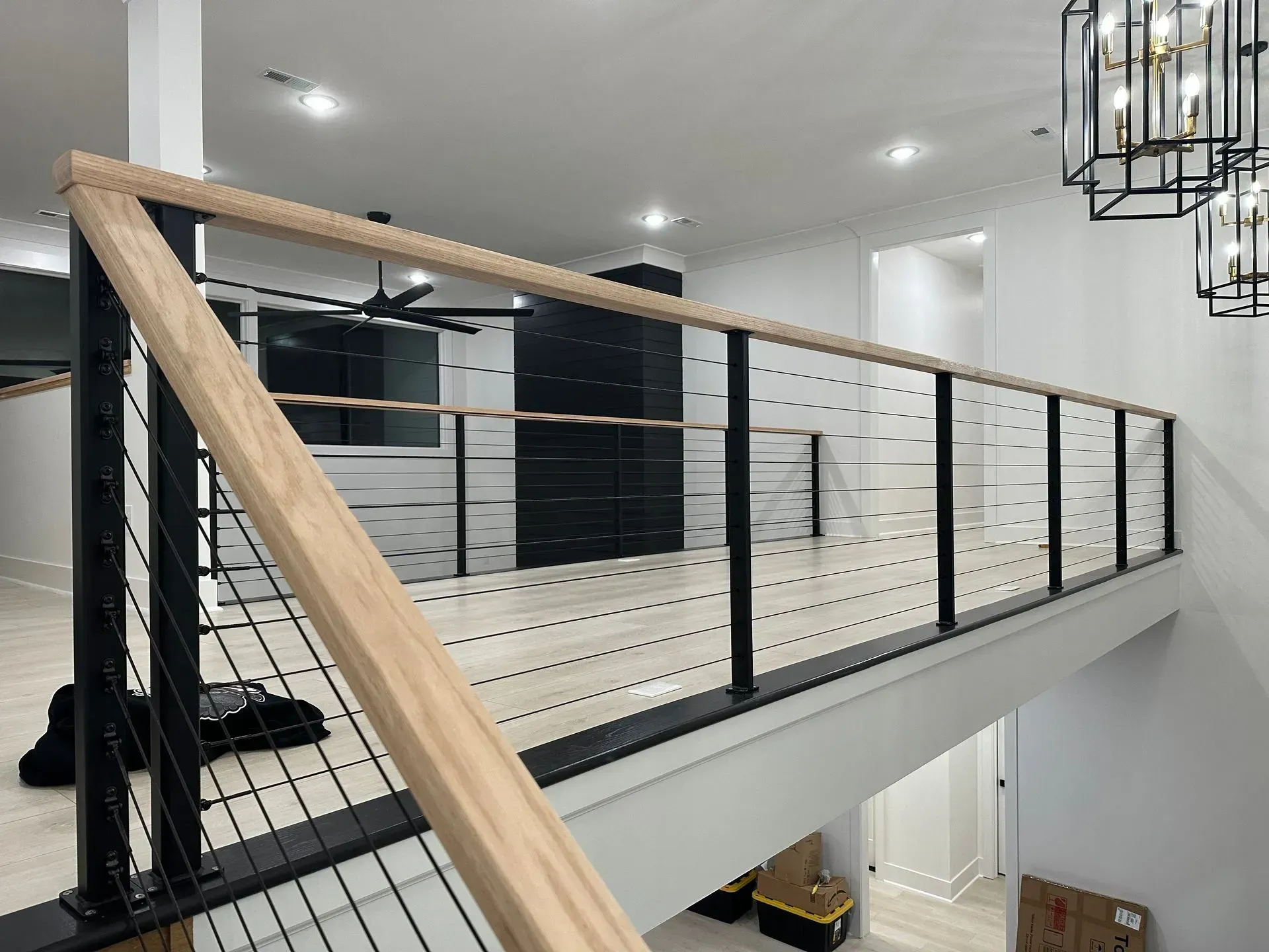 Modern interior: railing with black metal posts and horizontal cables, wood top rail.
