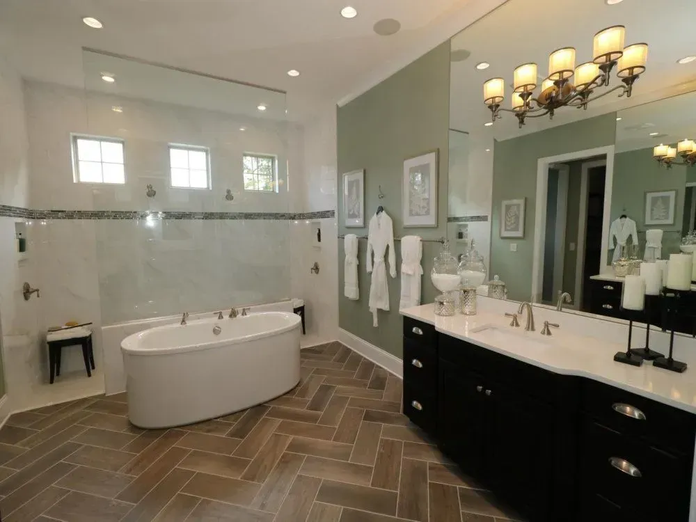 Luxurious bathroom with an oval bathtub, black vanity, and herringbone floor.