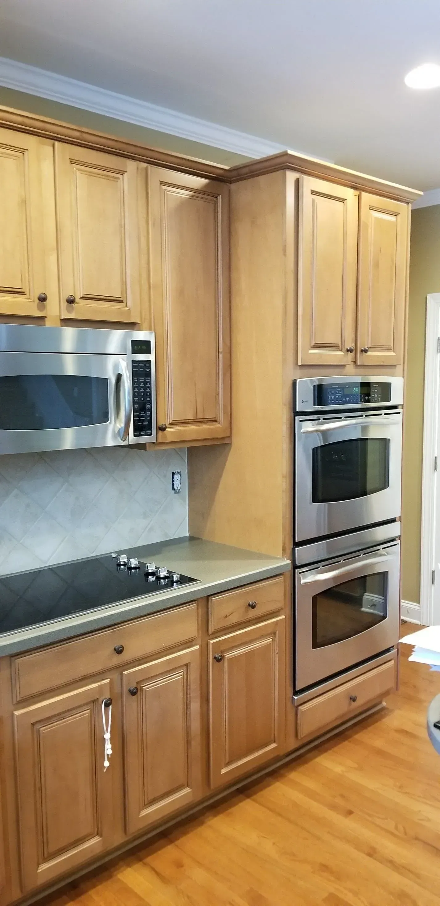 Kitchen with light brown cabinets, stainless steel appliances, and wooden floors.
