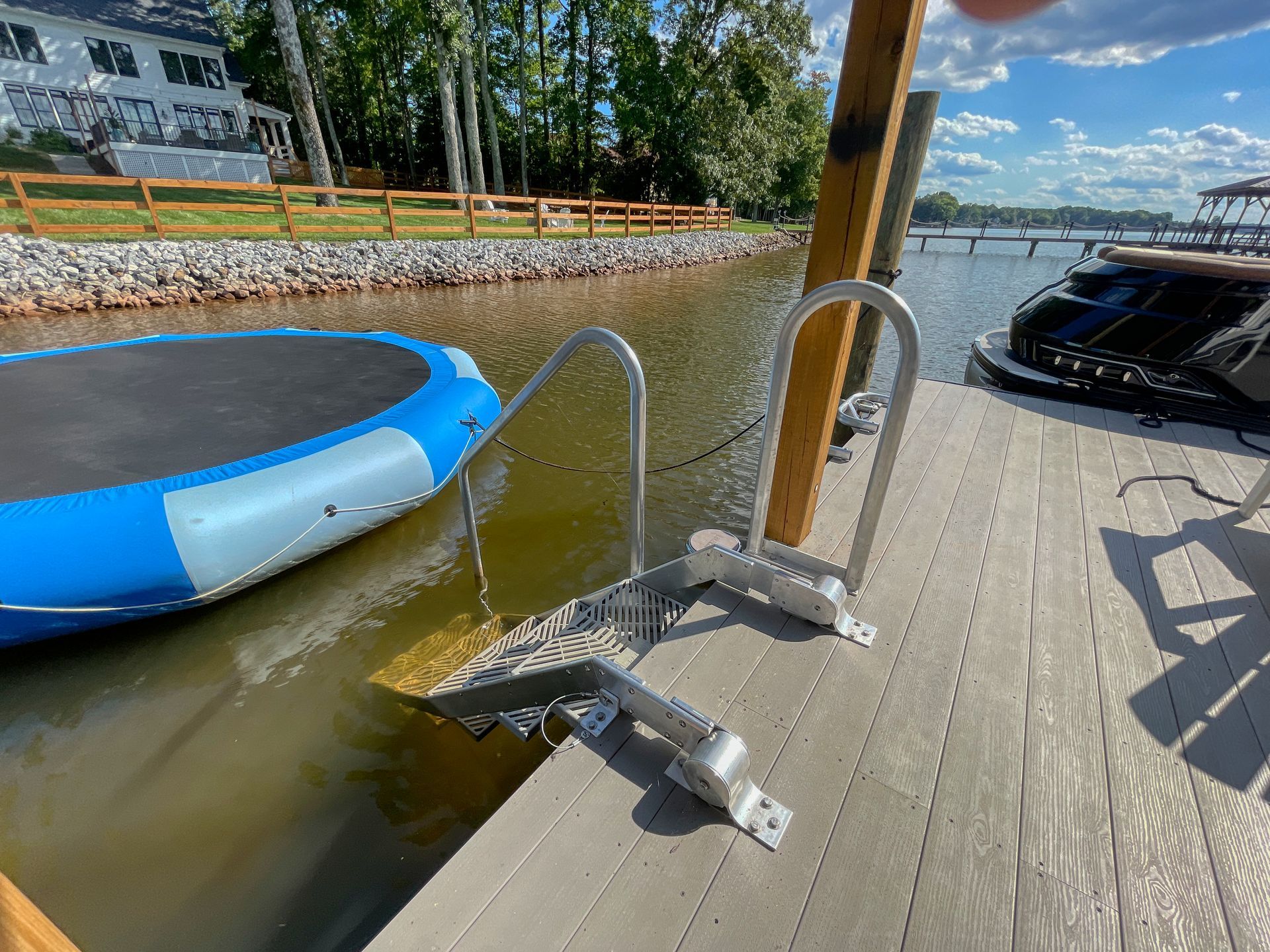 Aluminum boat ladder on a dock by water, next to a blue inflatable raft.