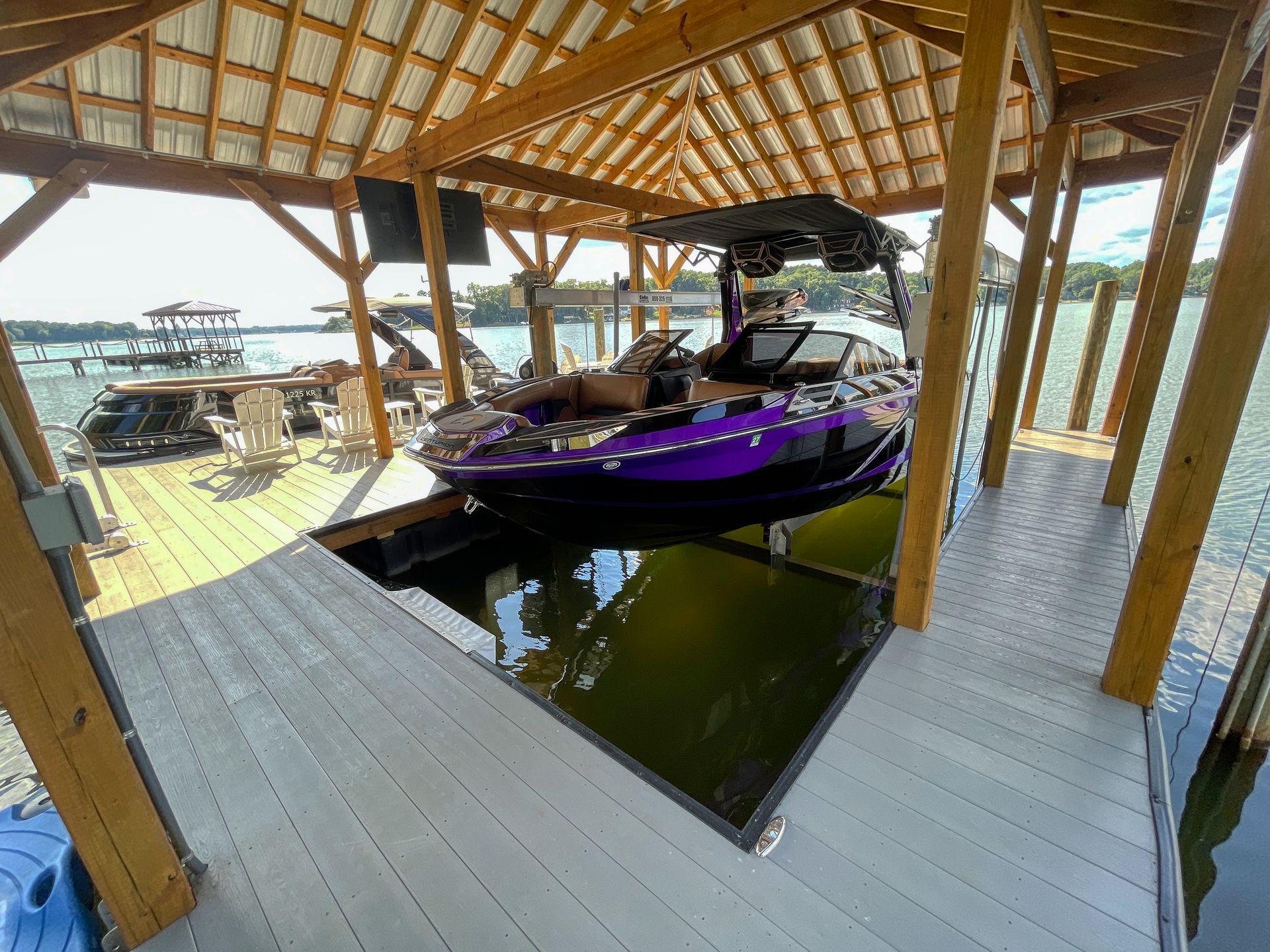 Boat in purple and black docked in a wooden boathouse on a lake.
