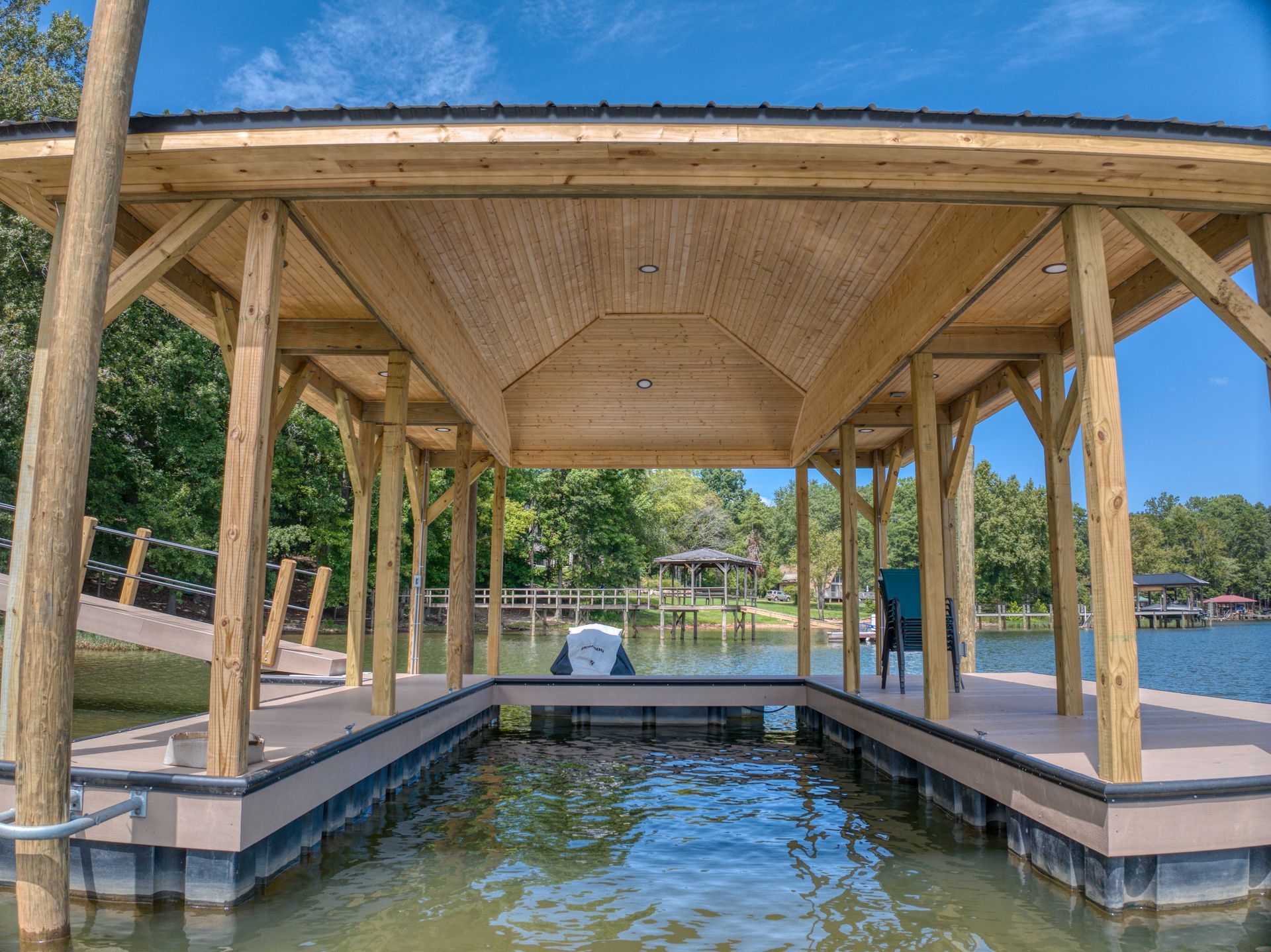 Wooden boat dock with canopy over a boat slip on a lake. Trees visible in the background.