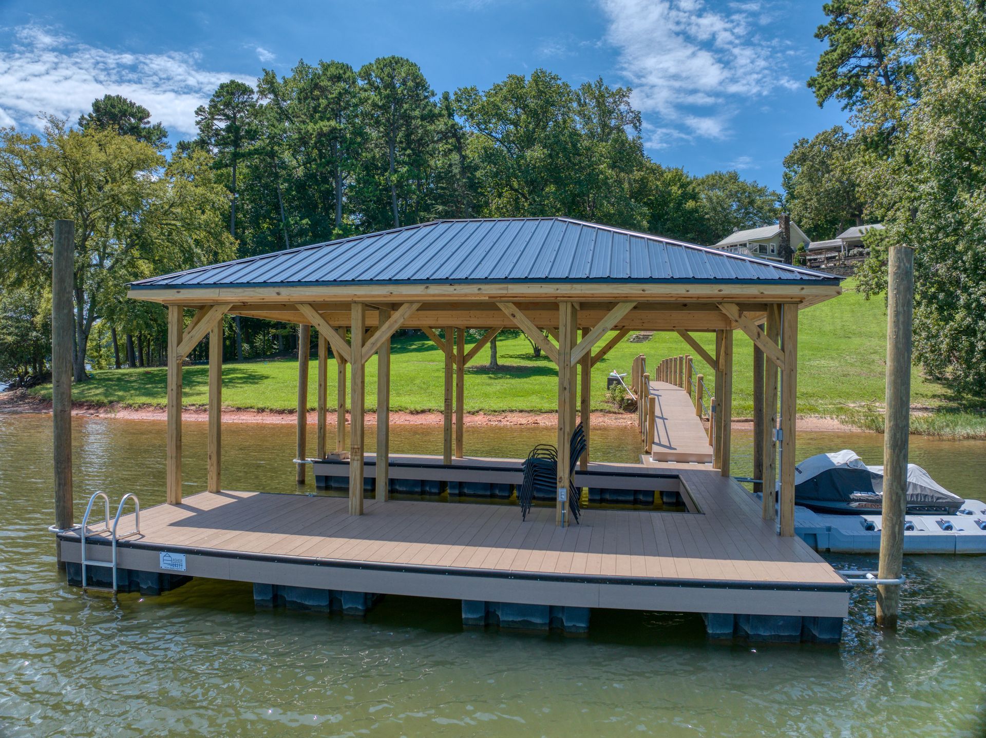 Dock with a covered structure on a lake, featuring a blue roof and wooden supports.