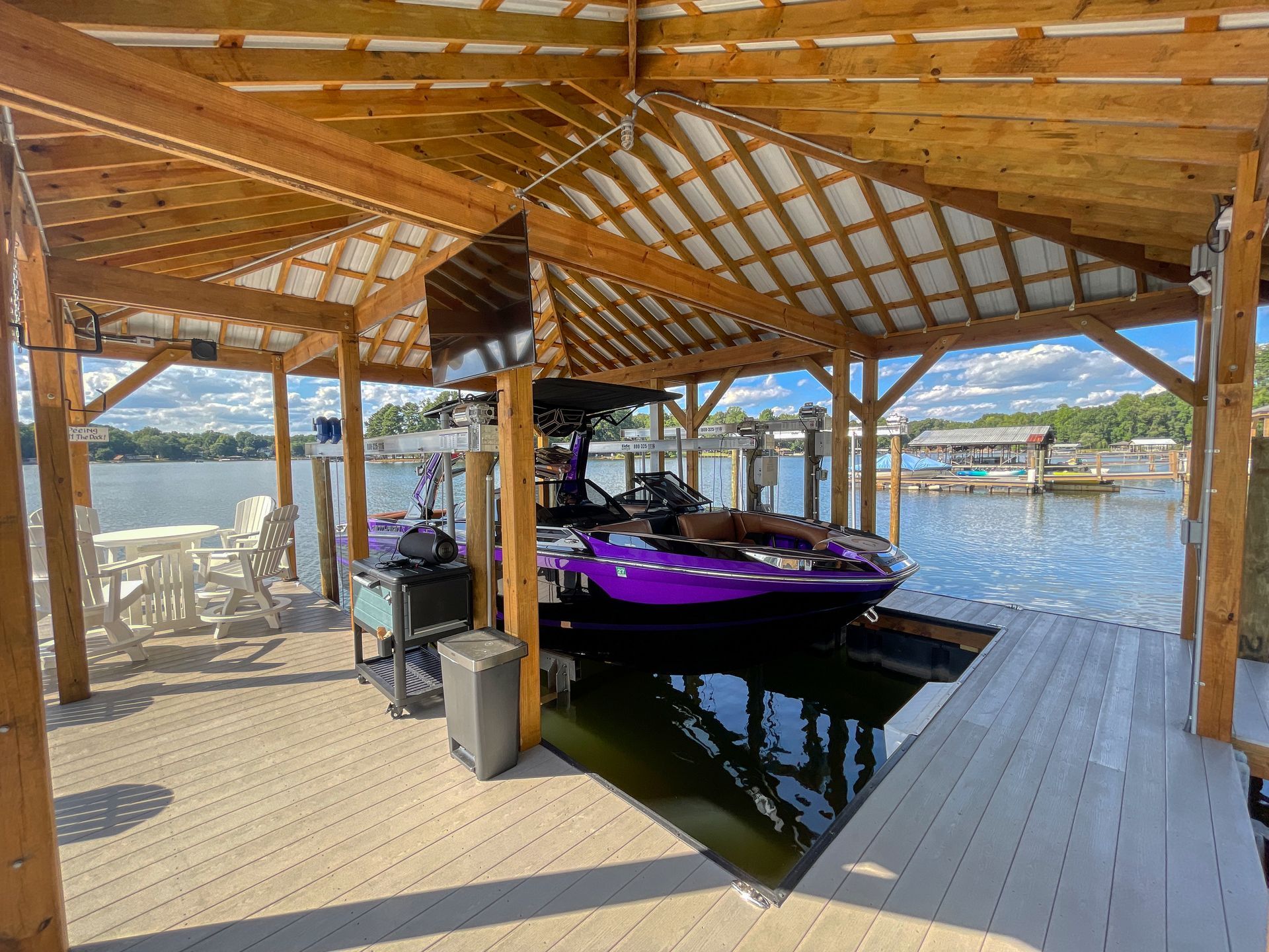 Dock with purple jet ski under a wooden roof. Lake in background.