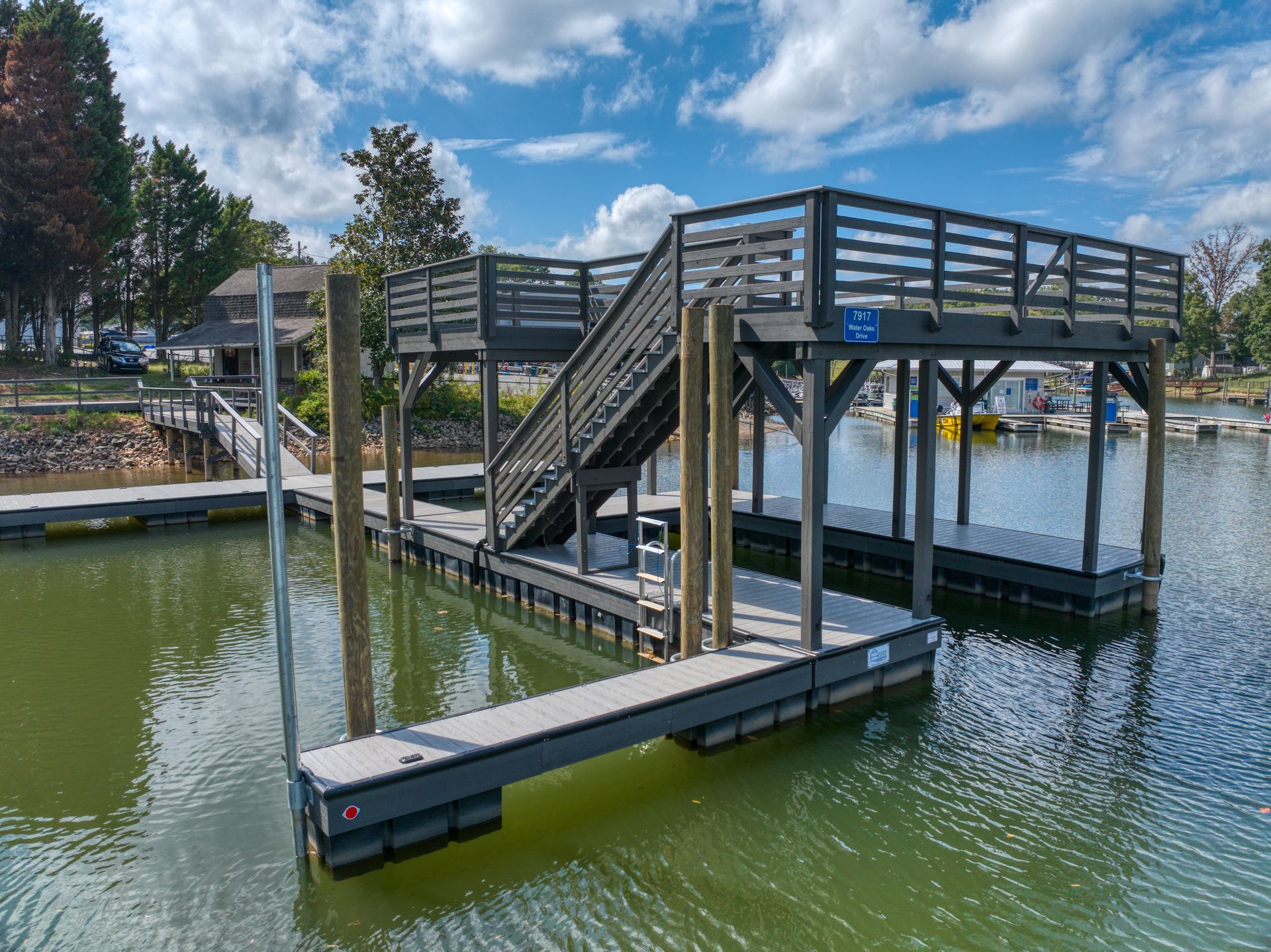 Floating dock with stairs leading to a raised platform on a lake; gray and brown.