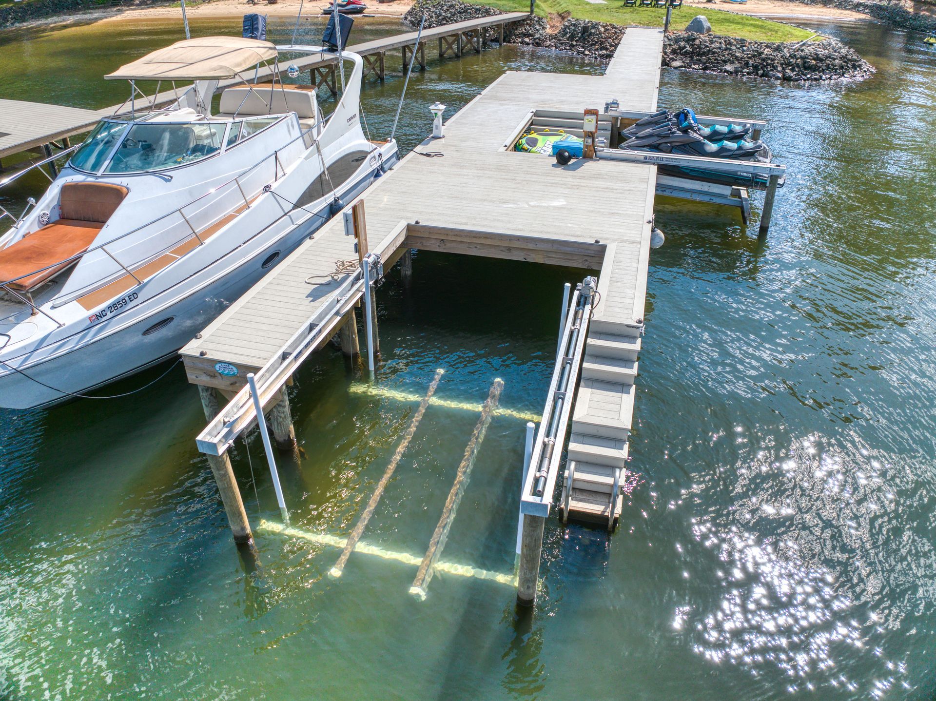 Boat dock with a boat and jet ski. Dock has stairs and a lift into the water.