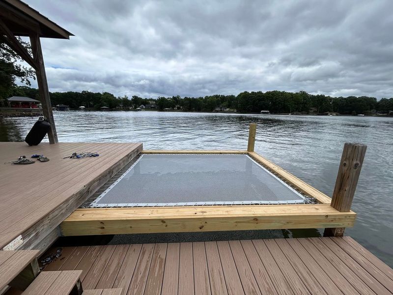 Wooden dock with a swim platform, overcast sky, lake in the background.