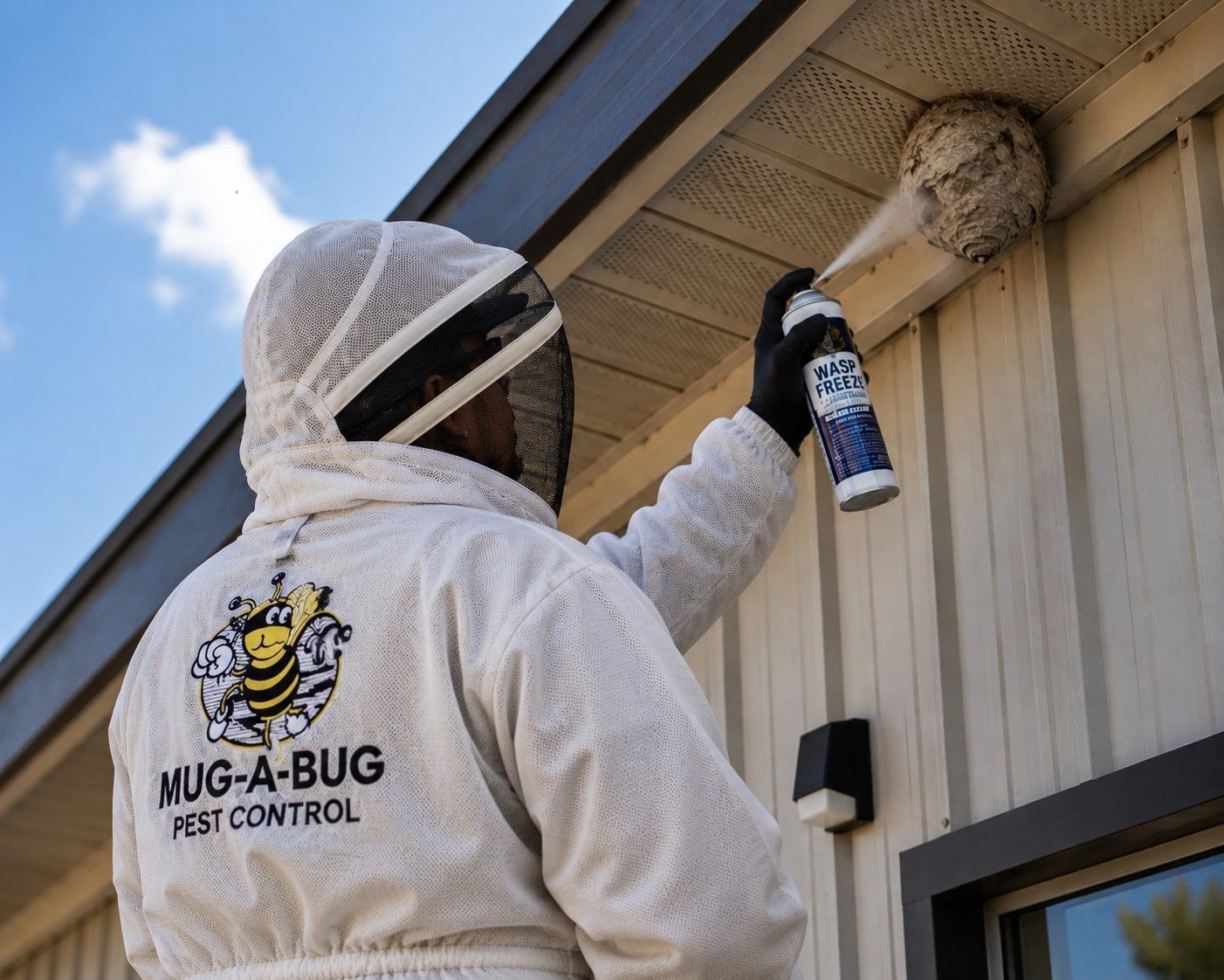 Pest control technician spraying under roof eaves of a house with a long-handled applicator.