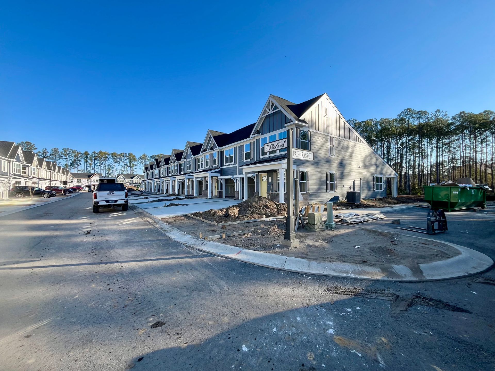 Row of new townhouses under construction, blue and white exterior, bright sunlight.