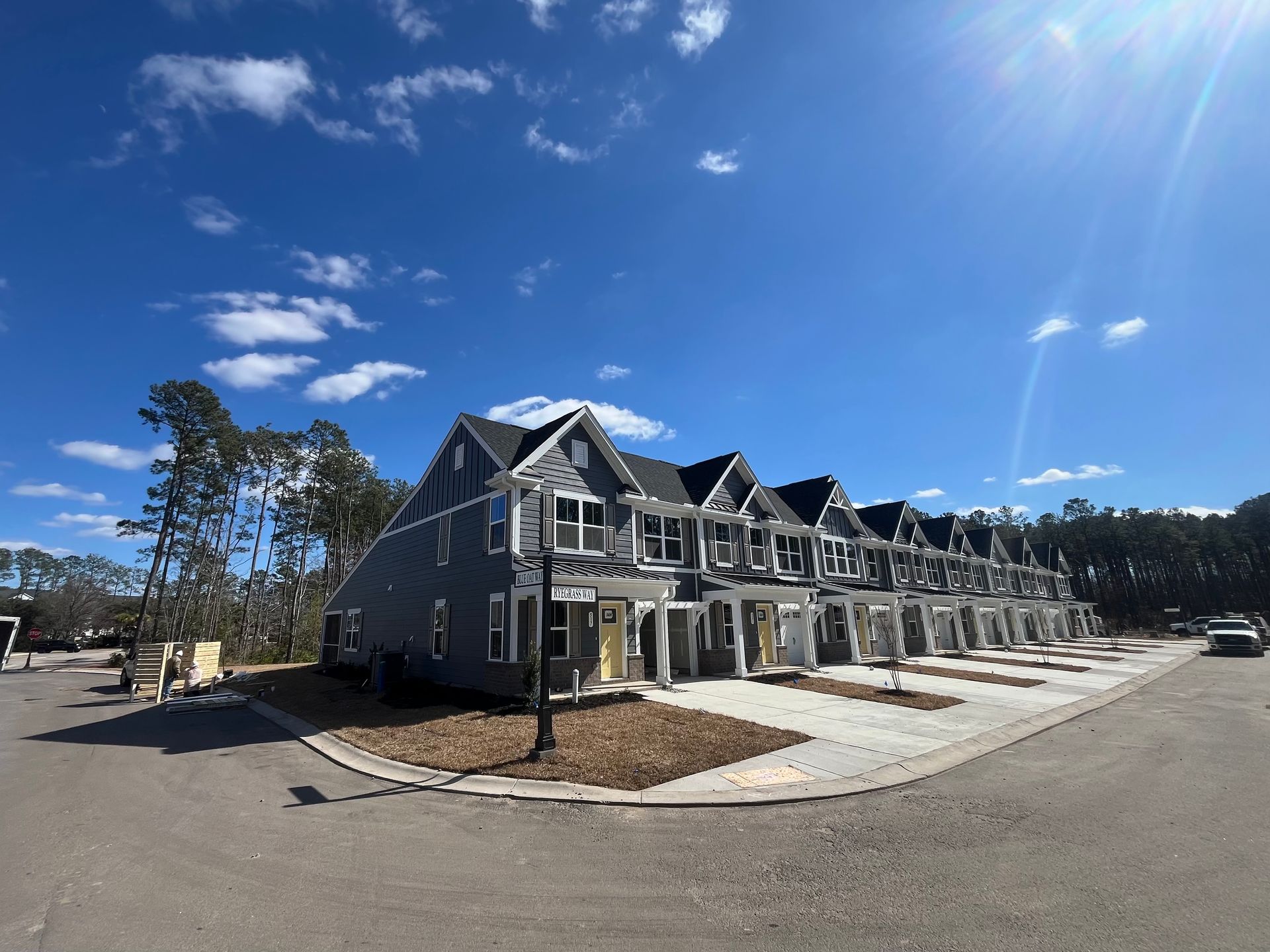 Row of gray townhouses with black roofs on a sunny day.