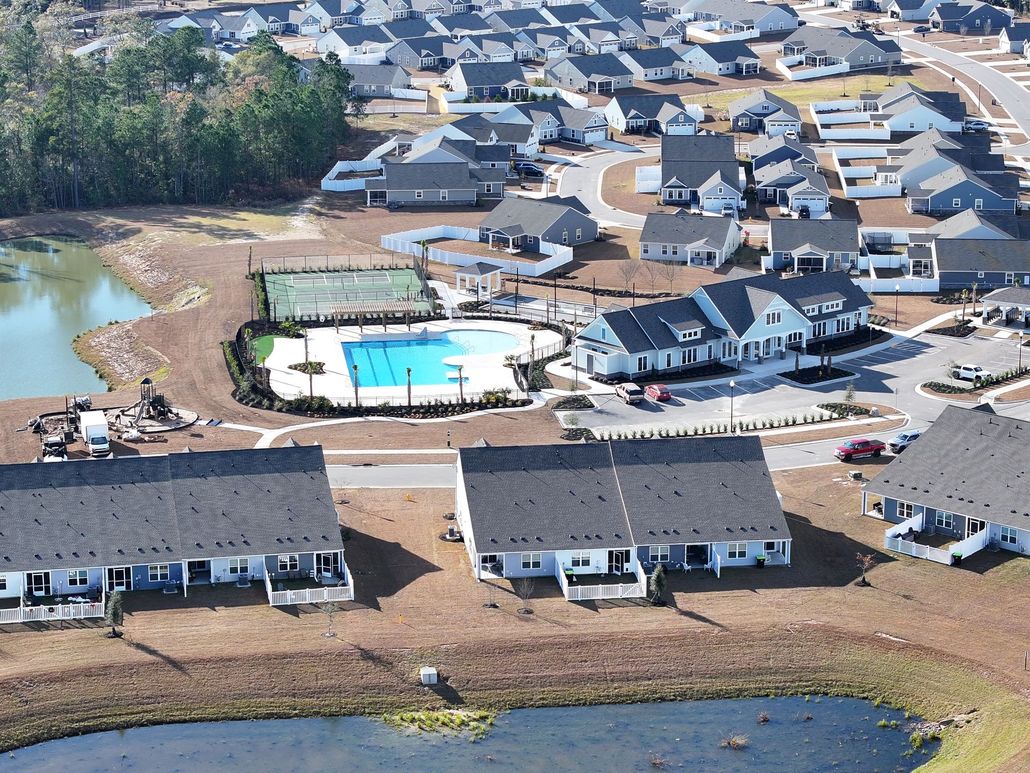 Aerial view of a residential neighborhood with a central community pool, tennis court, clubhouse, and surrounding ponds.