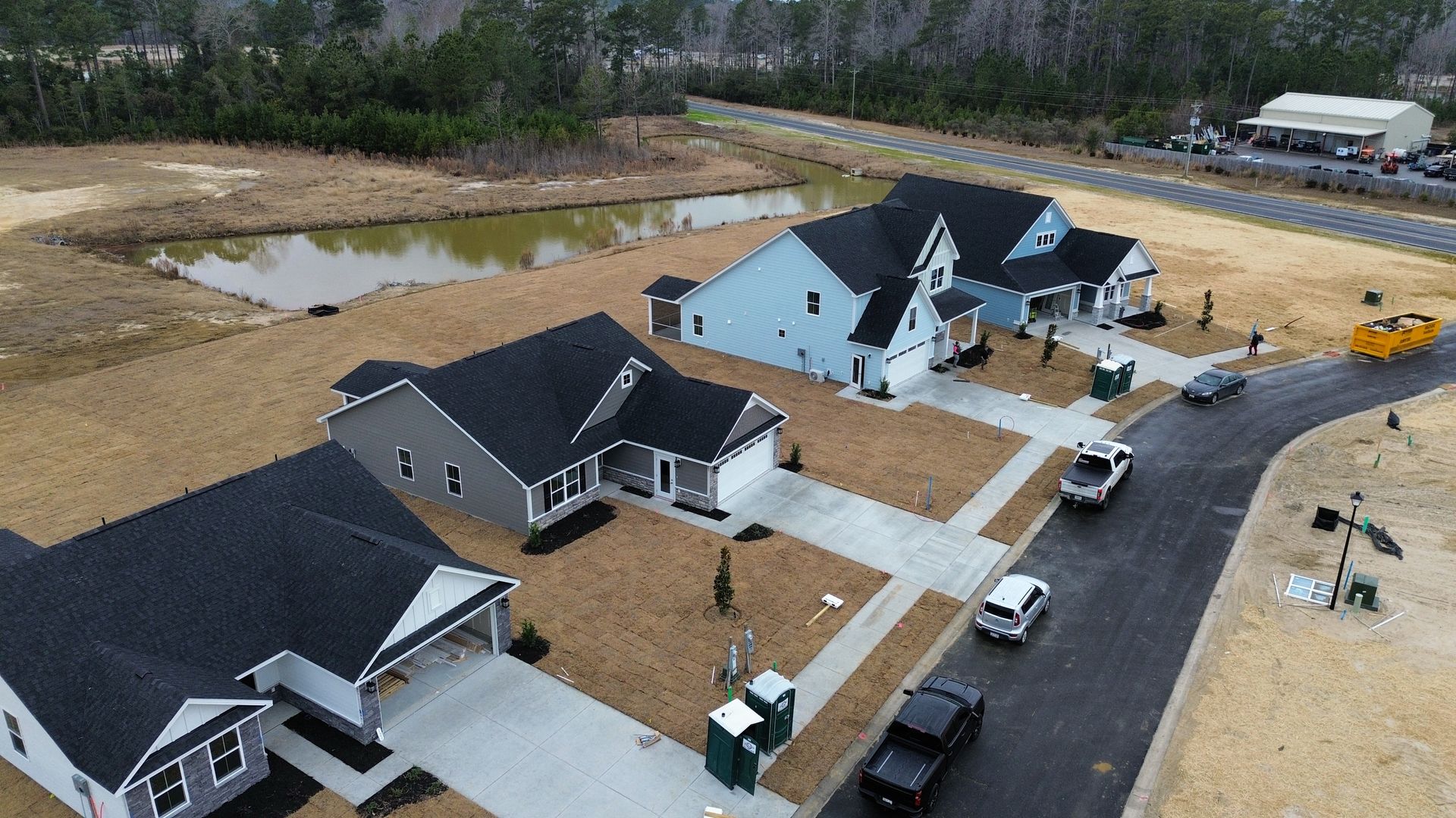 Aerial view of newly constructed homes in a development with a pond.