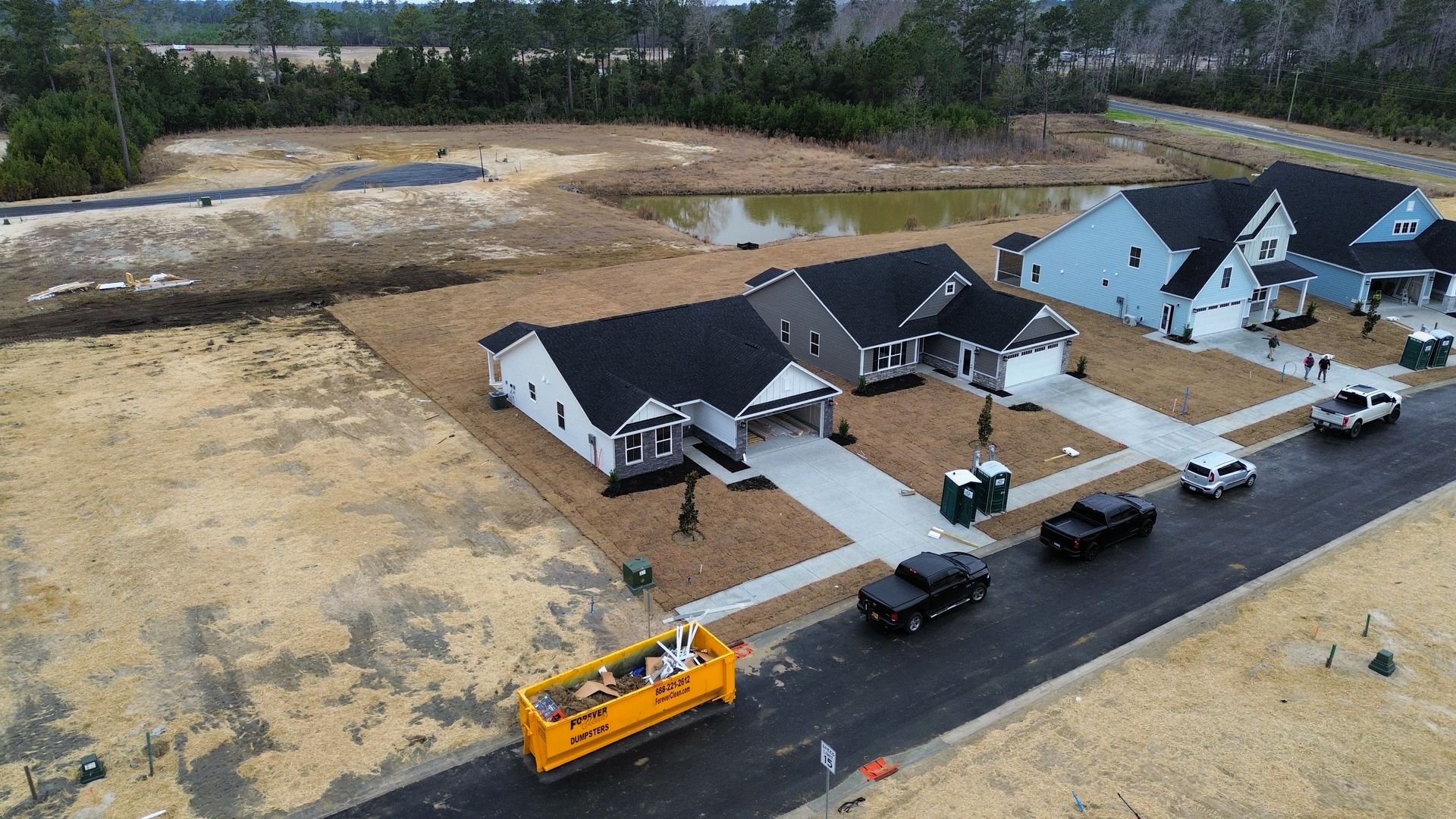 Aerial view of new homes under construction. Dump truck, cars on road.
