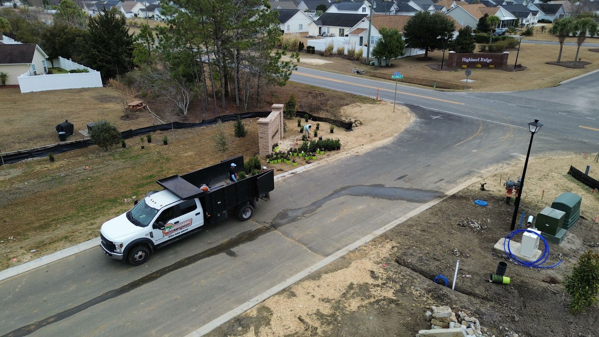 Work truck on a road in a residential area, with landscaping work in progress.