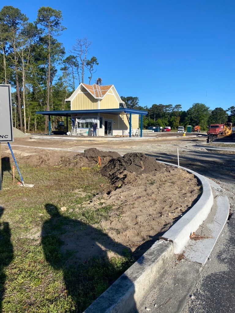 Construction site with a yellow building, blue awning, and dirt mound.