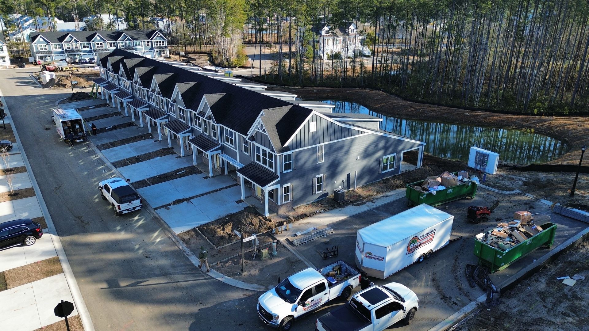 Row of gray townhouses under construction, with parked trucks and construction equipment.