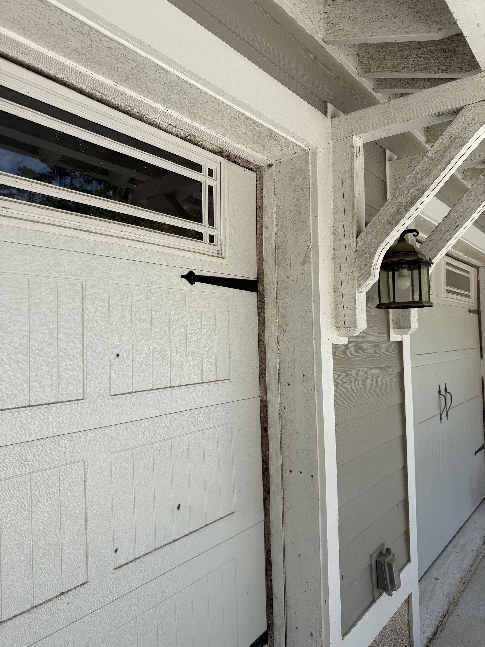 White garage door and side entry with a lantern under a covered porch