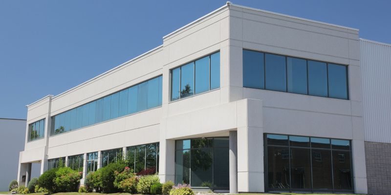 Modern white two-story office building with blue-tinted windows and glass entrance