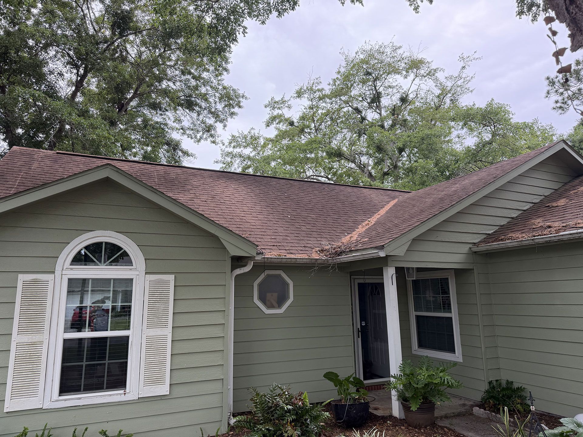 Single-story house with gray siding, red-brown roof, white shutters, and a small front porch.
