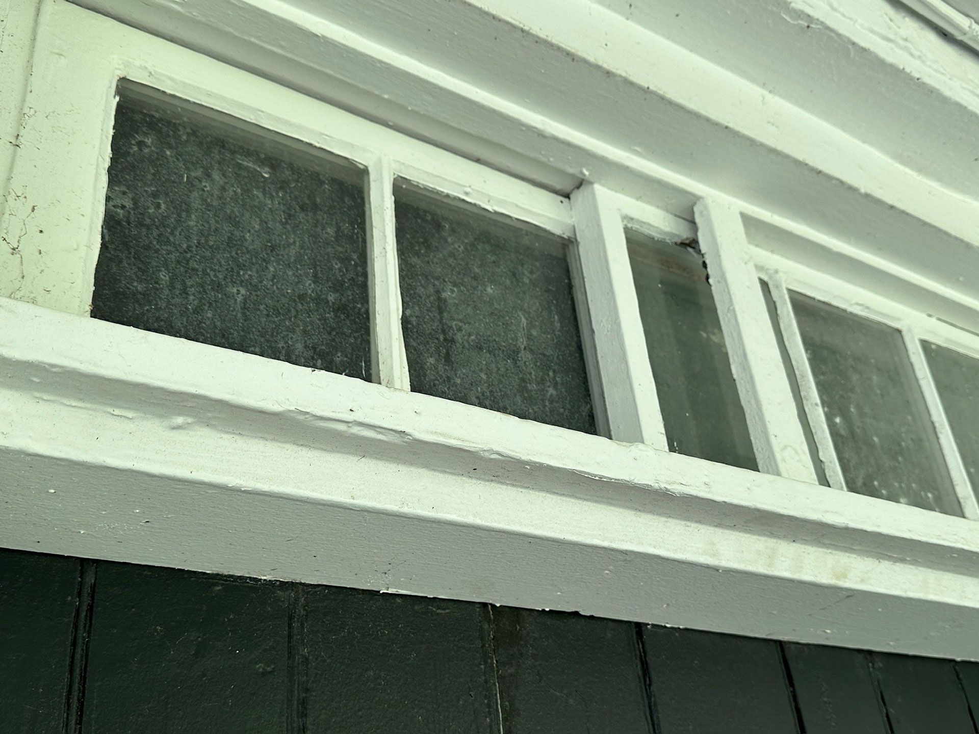 Close-up of white-framed windows on a dark green building exterior
