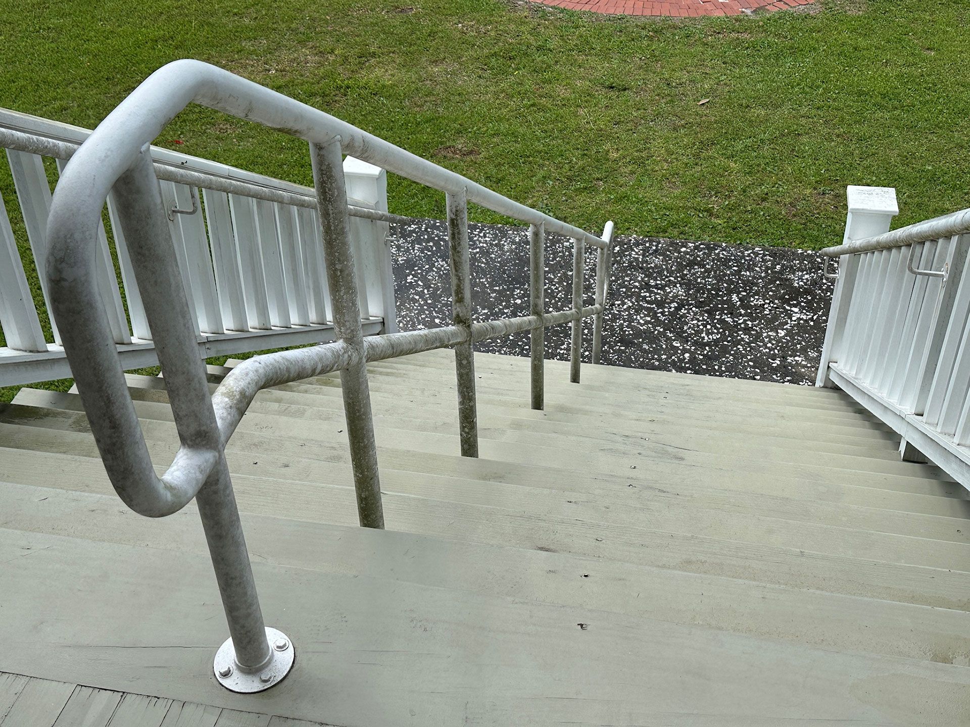 Steep concrete stairway with metal handrails leading down to a grassy area