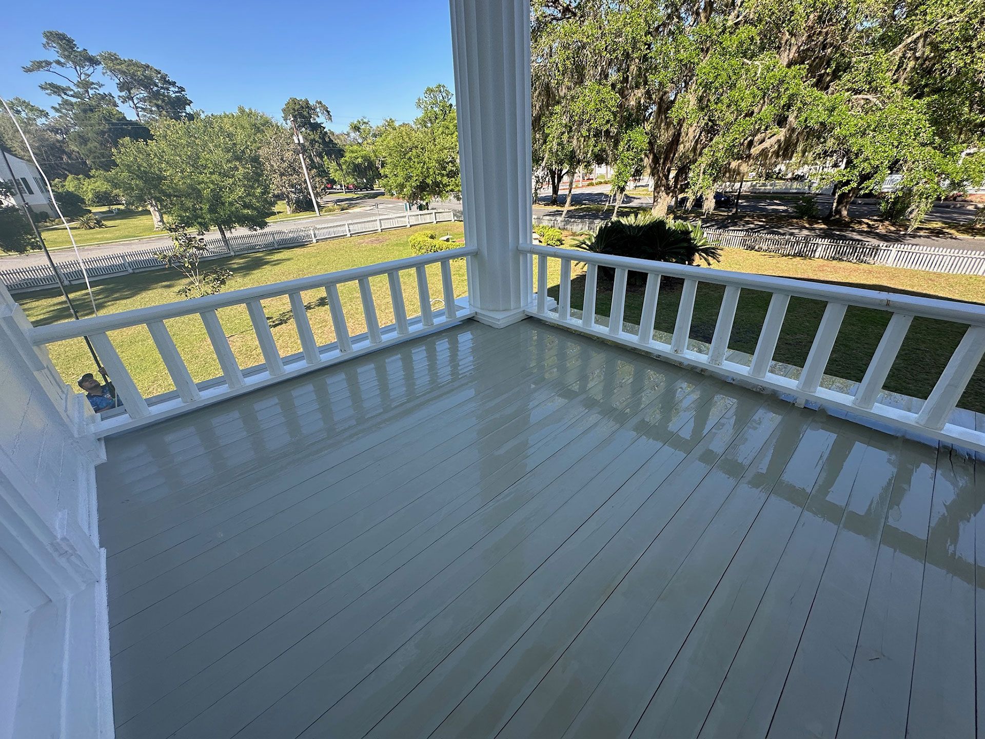 White gazebo porch with railings overlooking a sunny park and pond