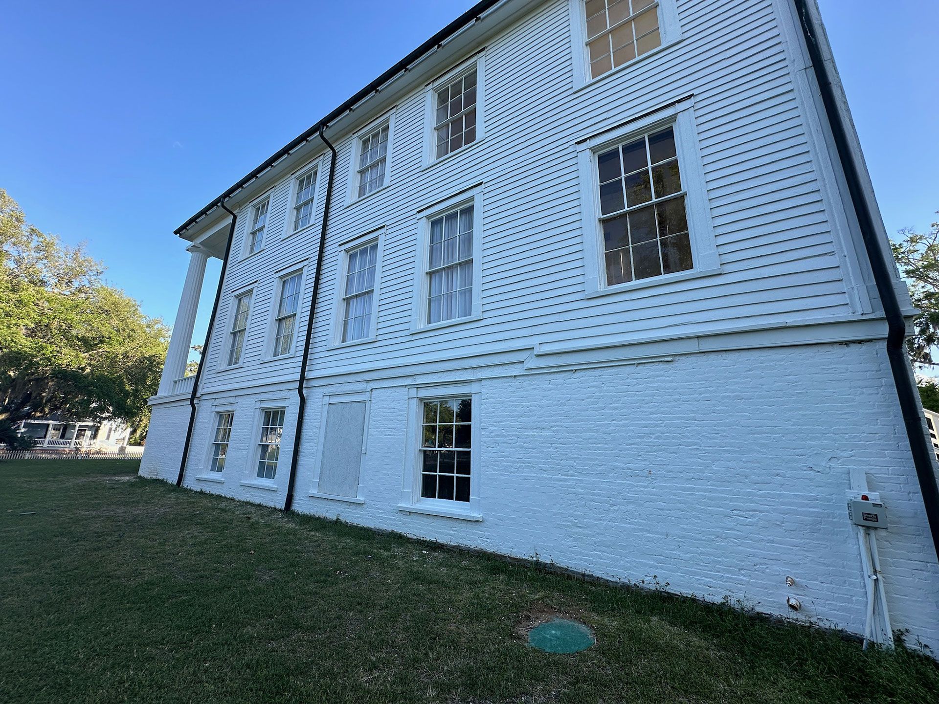 White two-story house with multiple windows, white siding, and a grassy yard under a clear blue sky