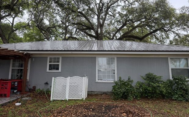 Gray house with white trim, red porch, and a small white fence under trees