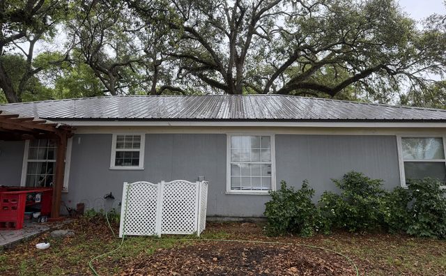 Gray house with white trim, red porch, and a small white fence under trees