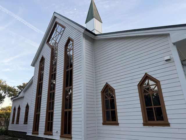 White church exterior with tall arched windows and a steeple against a blue sky