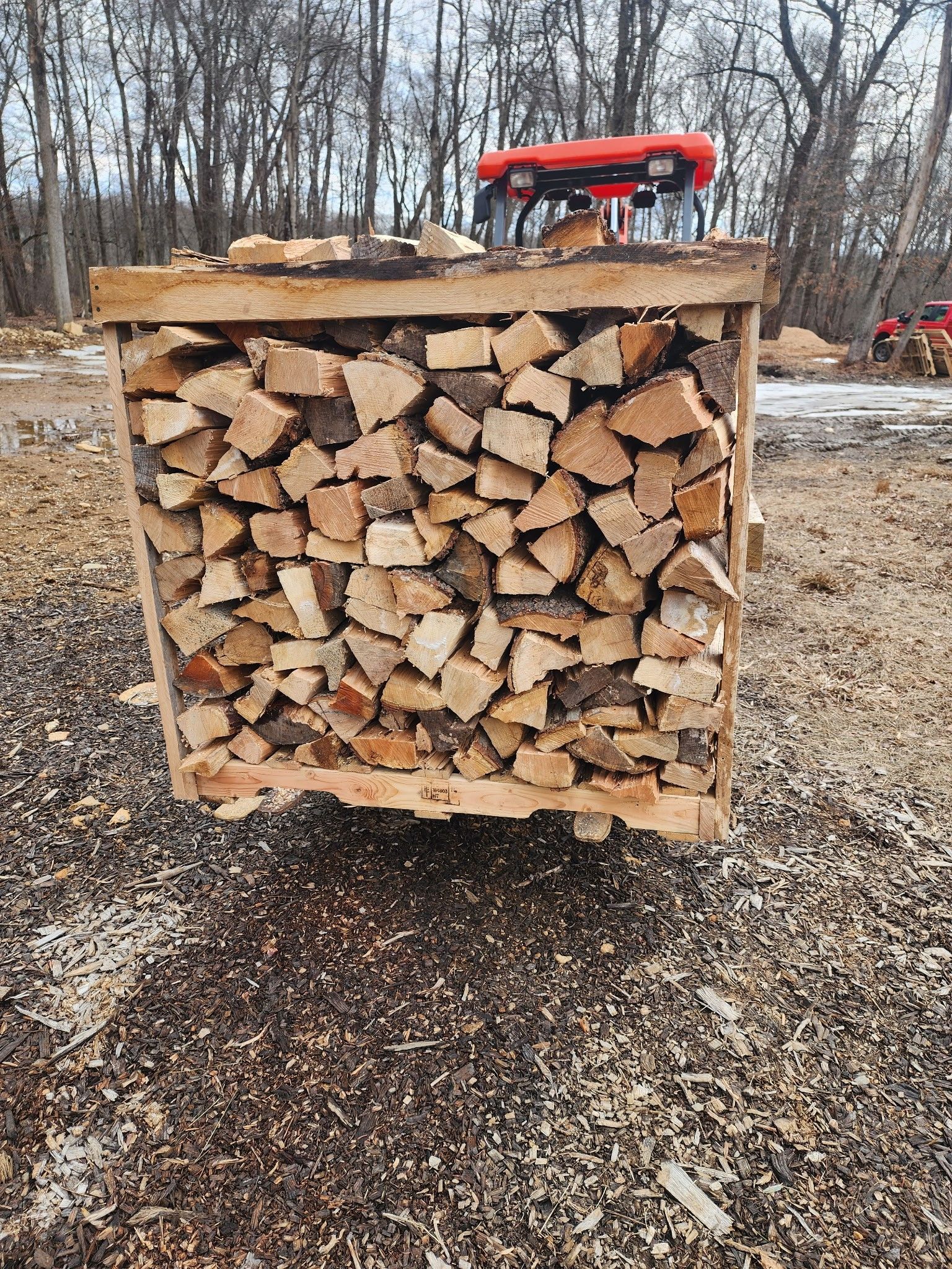 A wooden crate filled with logs is sitting on top of a pile of wood.