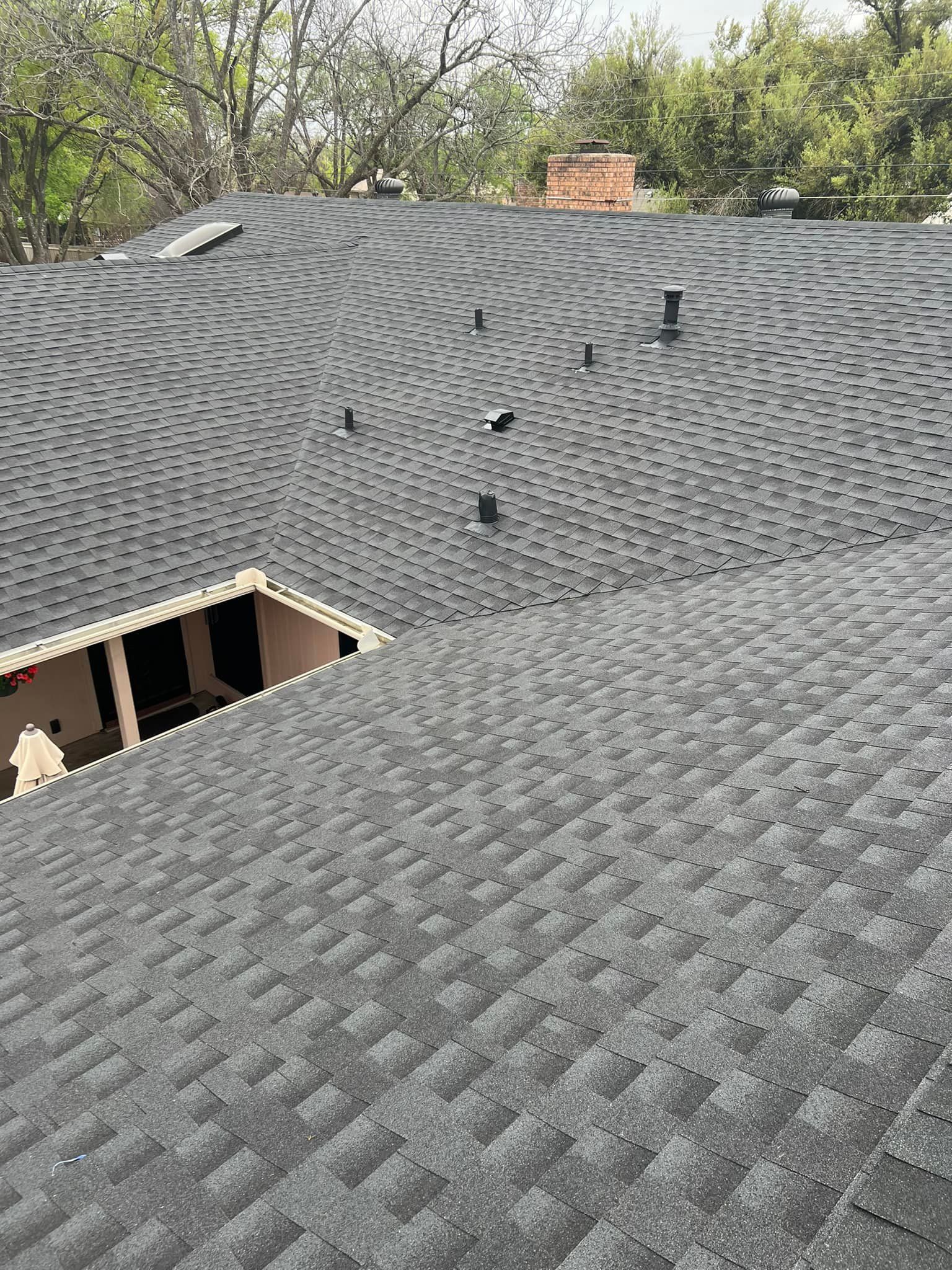 Roof covered in gray asphalt shingles with several vents and an open section near the edge