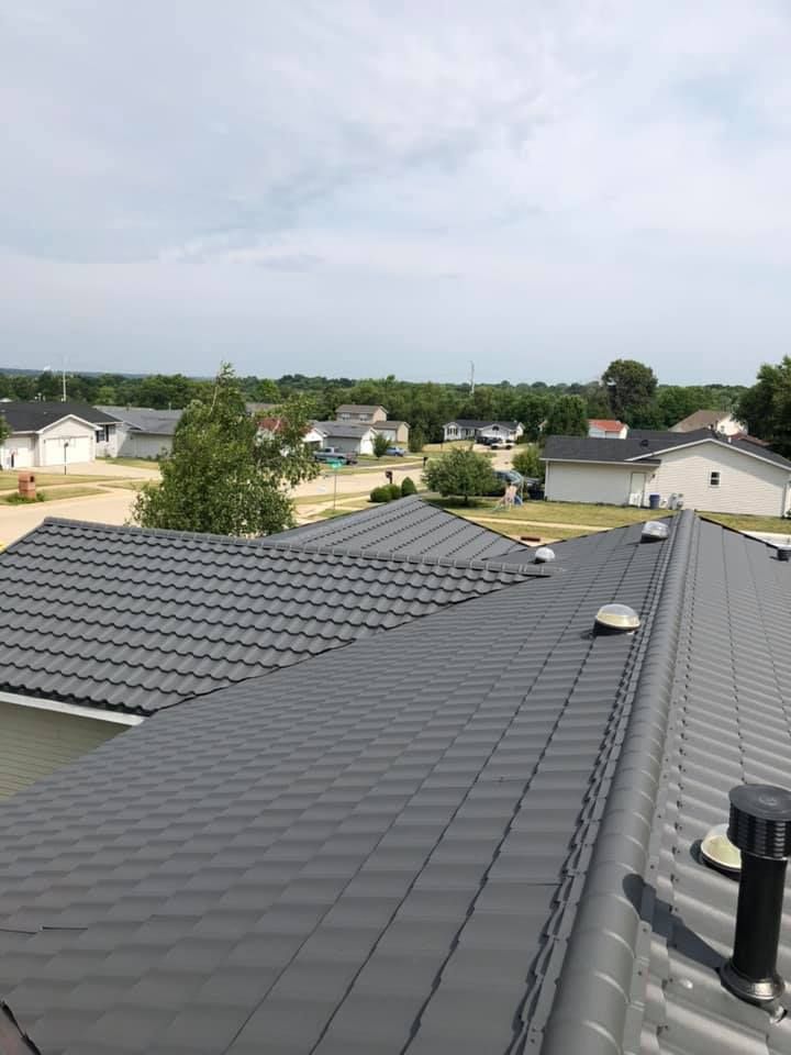 View from a gray tiled rooftop over a suburban neighborhood under a cloudy sky