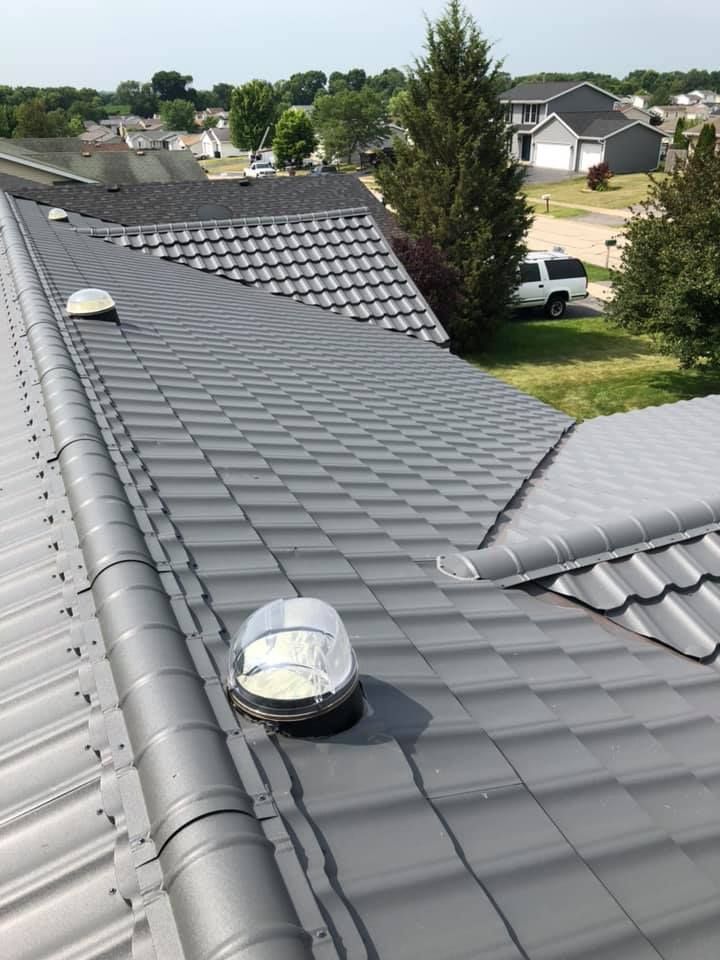 Black tiled roof with skylights overlooking a suburban neighborhood under clear skies