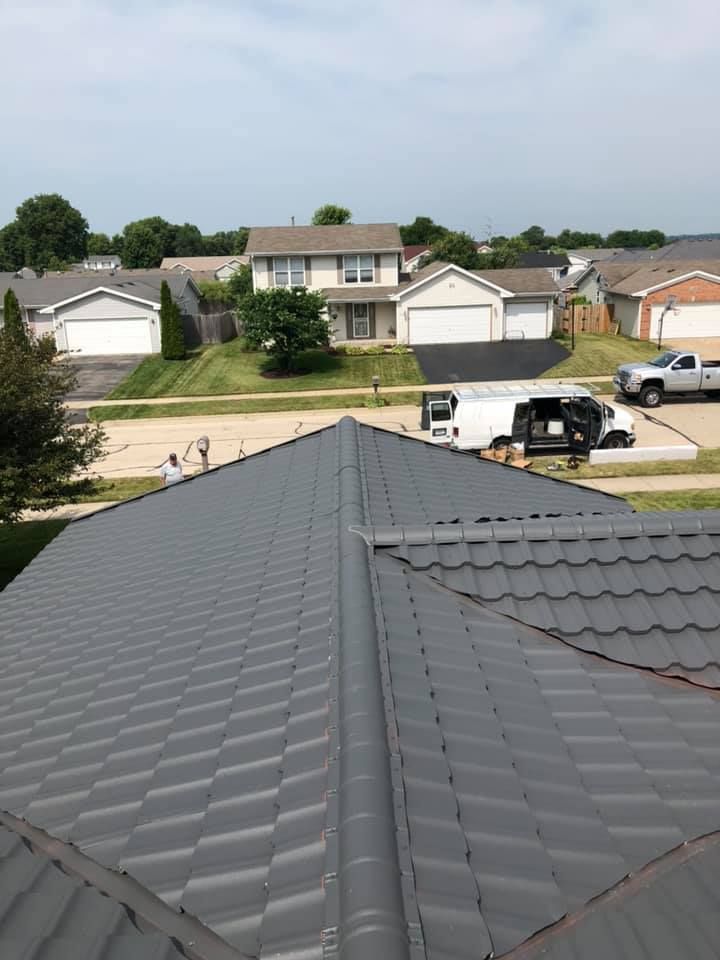 View from a dark gray roof over a suburban street with houses, lawns, and a white van parked below.