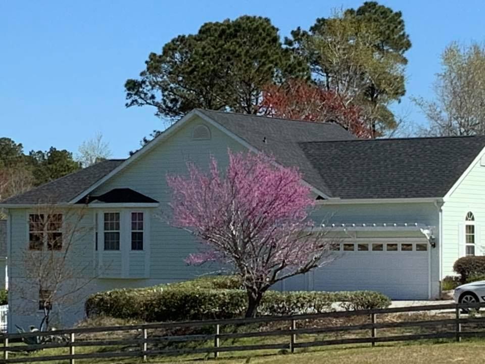 Suburban house with white siding, garage, and a pink flowering tree in front