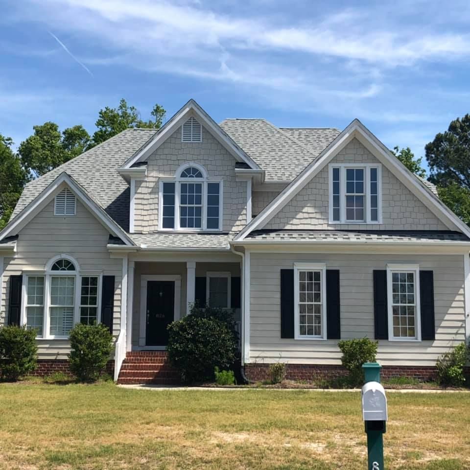 Gray suburban house with white trim, front porch, brick steps, and a mailbox in the yard