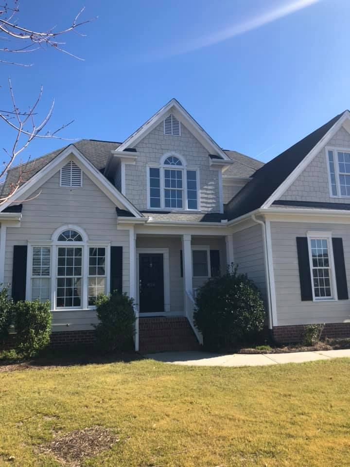 Suburban house with gray siding, white trim, front porch, and lawn under a clear blue sky