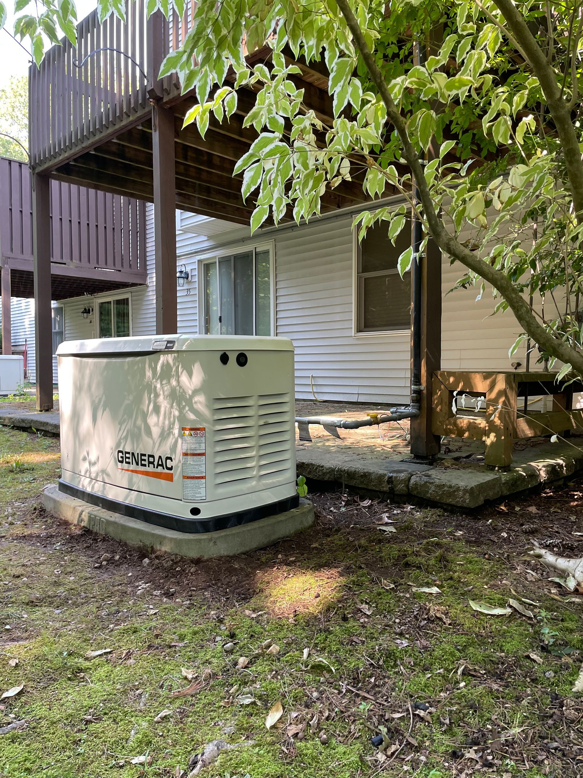 A generator is sitting in the grass in front of a house.