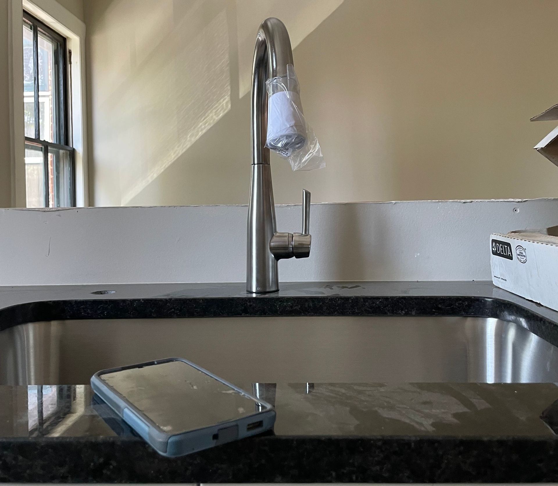 A kitchen sink with a faucet and a tablet on the counter