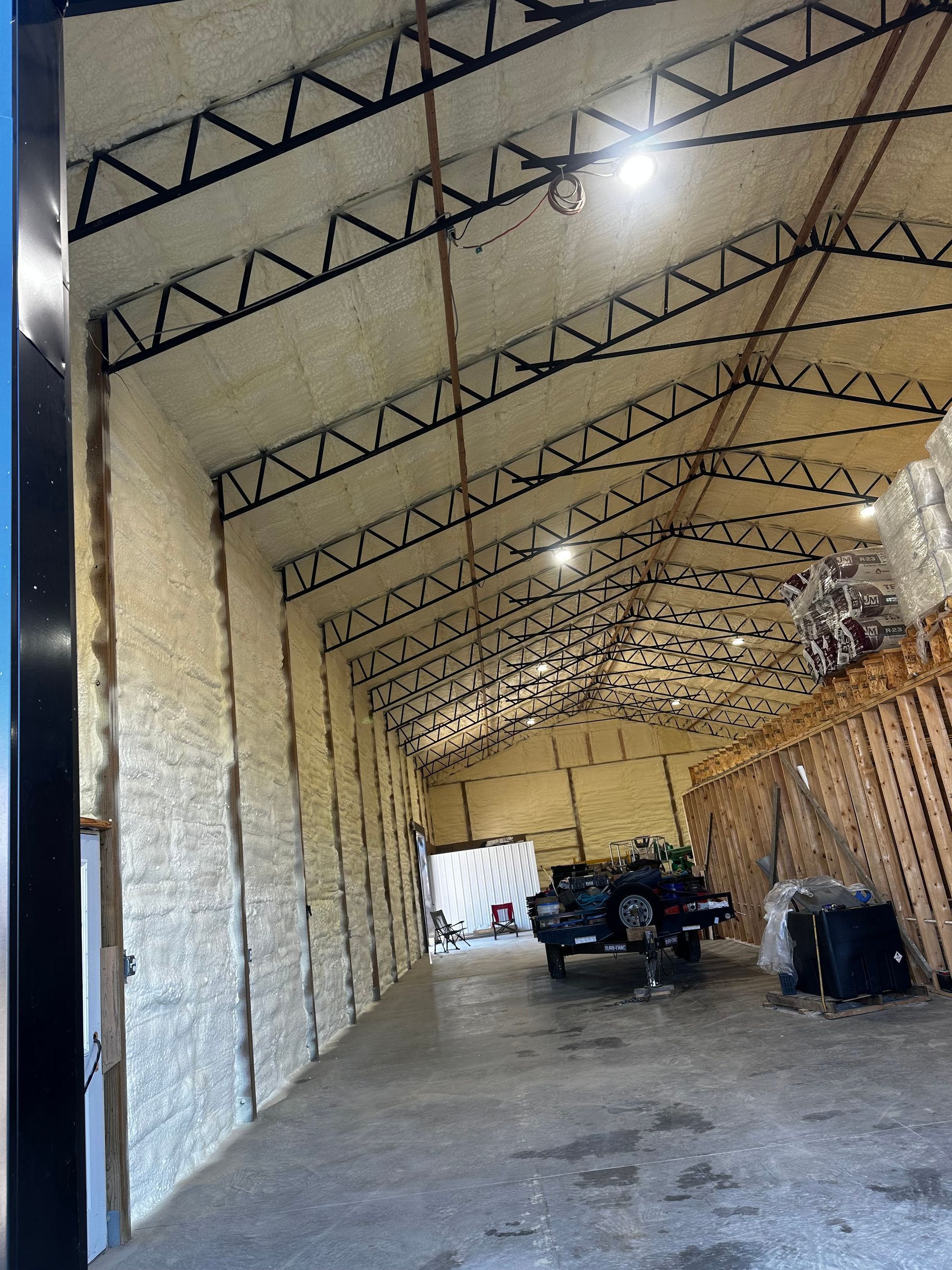 Interior of a warehouse with spray foam insulation on walls and ceiling. A vehicle sits inside.