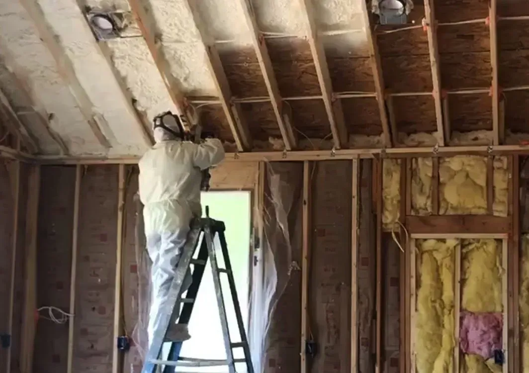 Man in protective suit spraying foam insulation in a home.