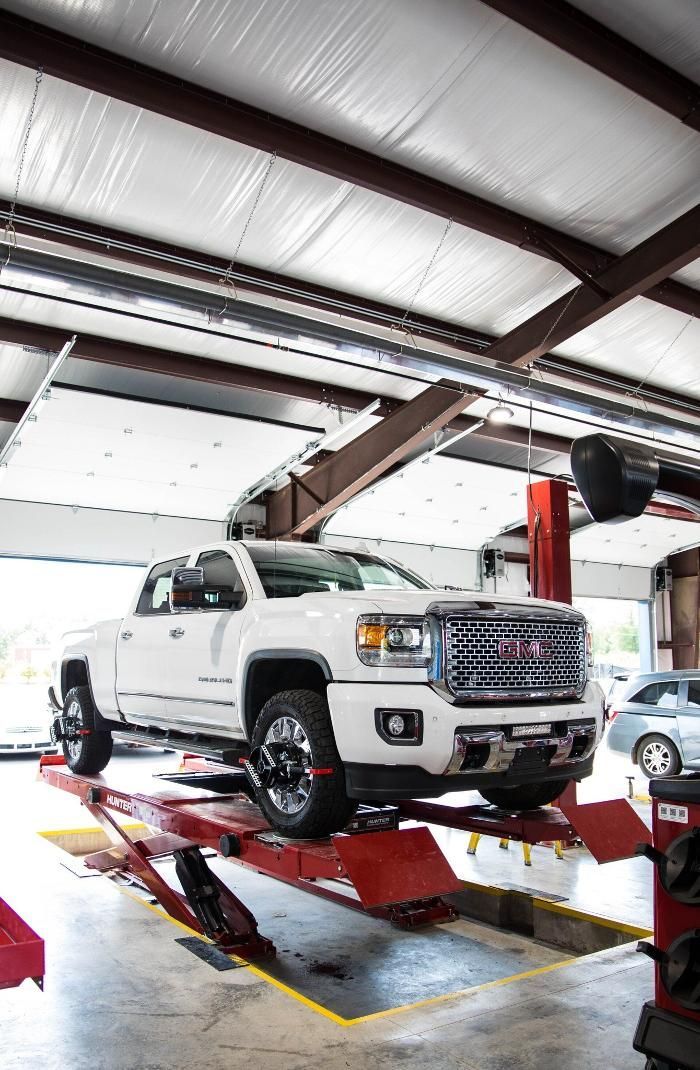 A white truck is sitting on a lift in a garage.