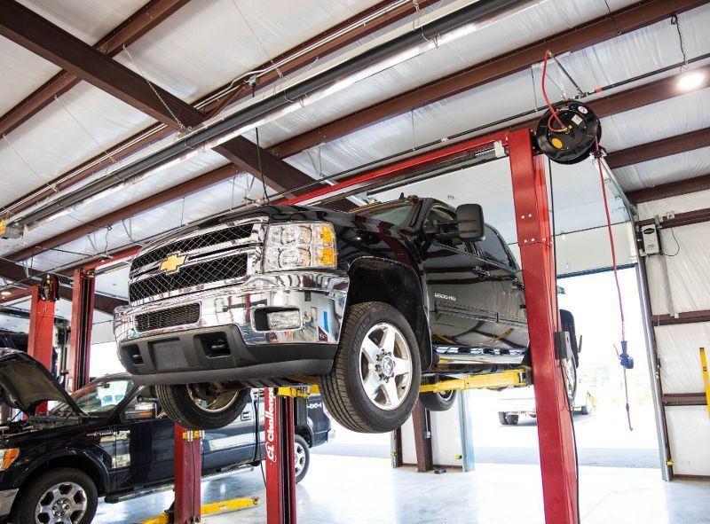 A truck is sitting on a lift in a garage.