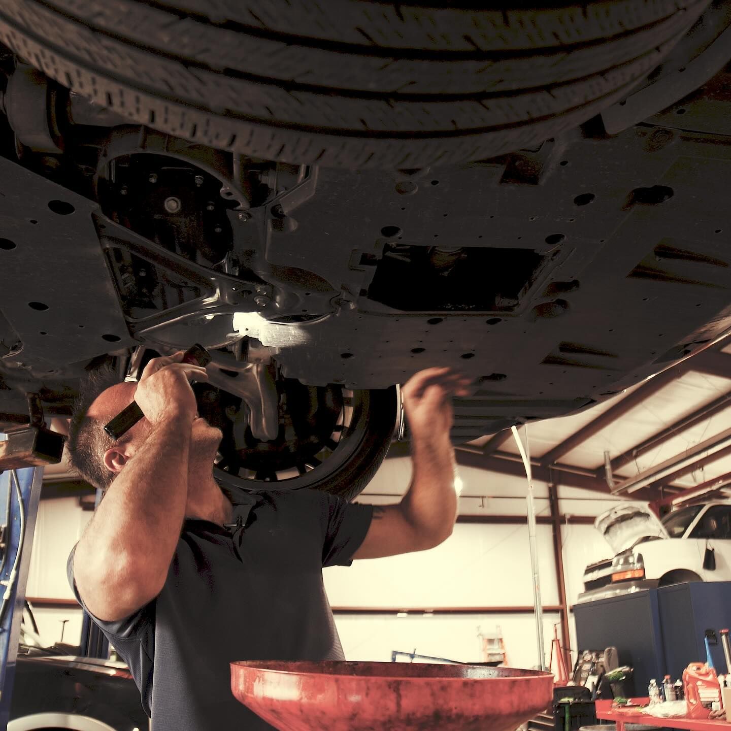 A man is working under a car in a garage